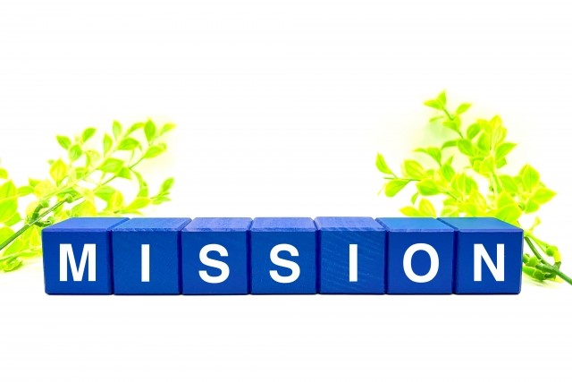 植物を背景に並ぶ青い積み木に書かれた「MISSION」の文字